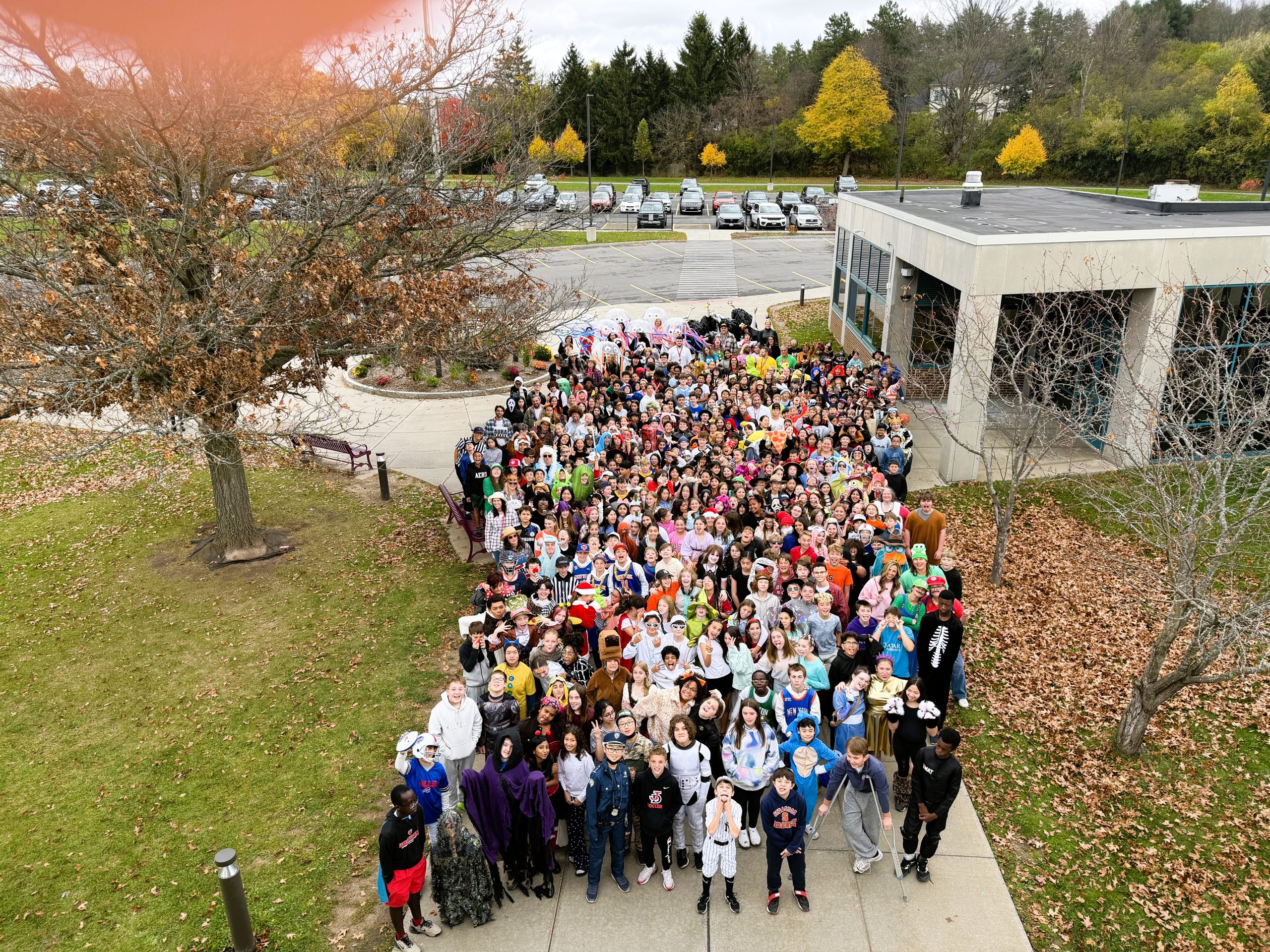 Large group of students stand outside school for Halloween group photo.