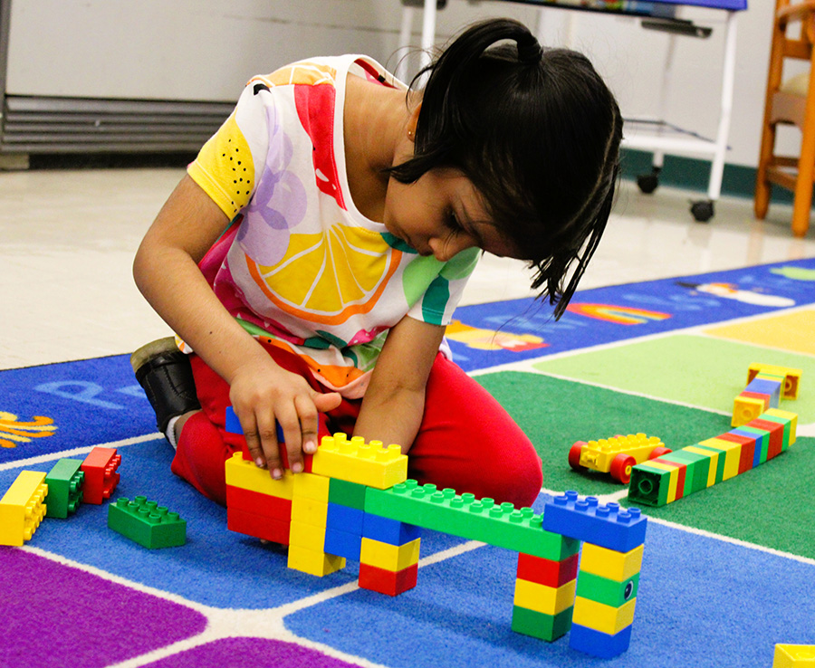 UPK student plays with legos on floor.